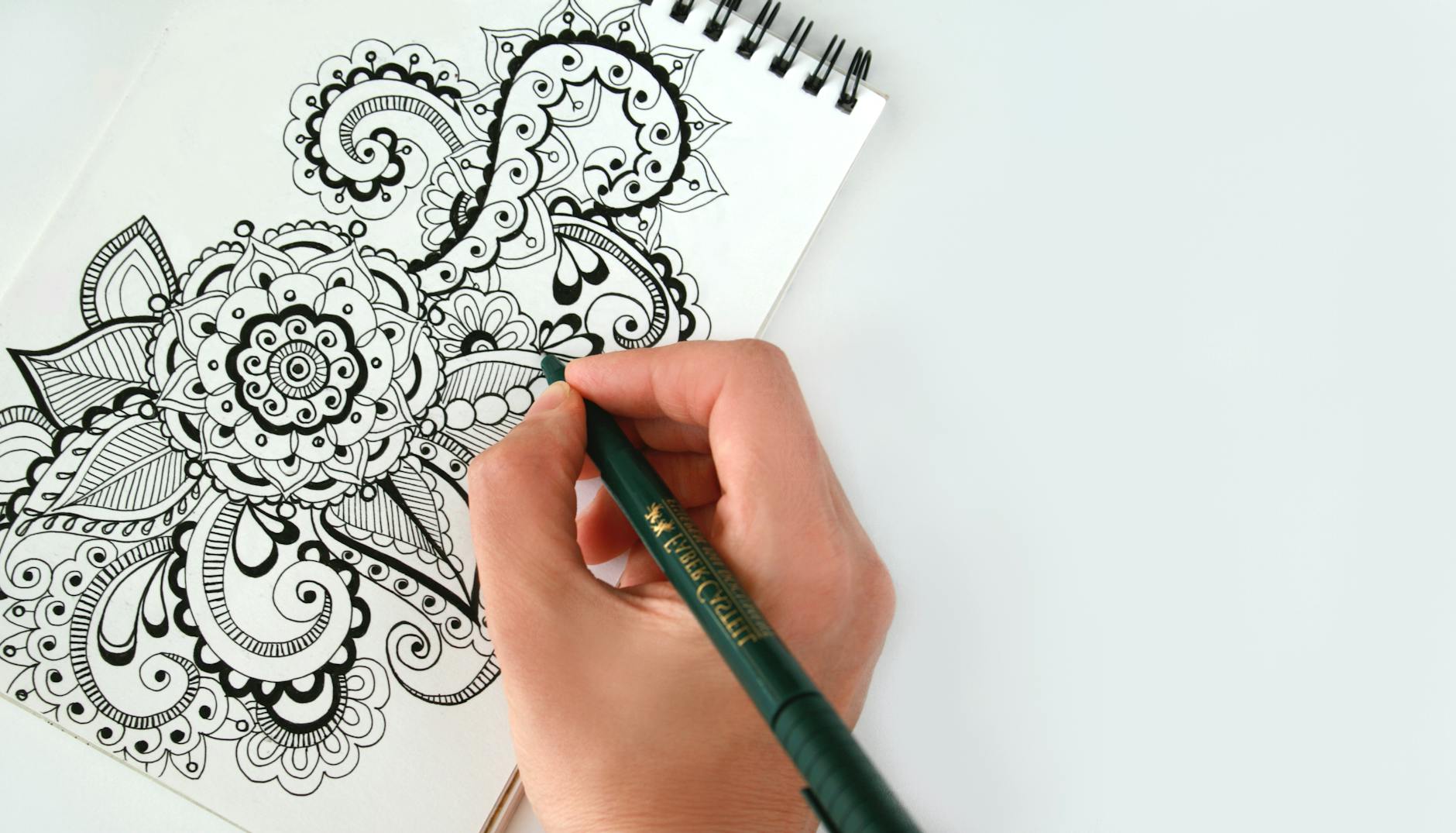 person holding black pen sketching flower