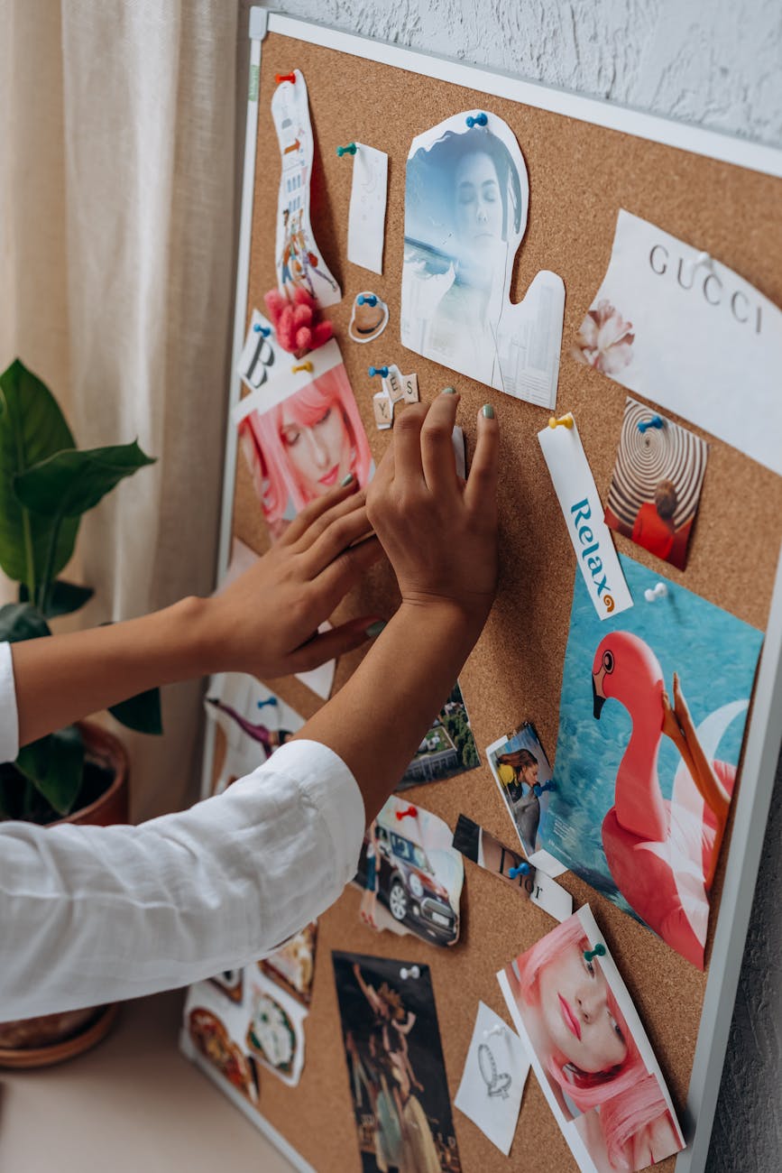 a hand sticking cut out magazine on a cork board